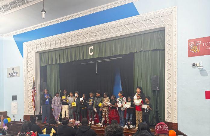 clark students stand on stage holding newly acquired awards